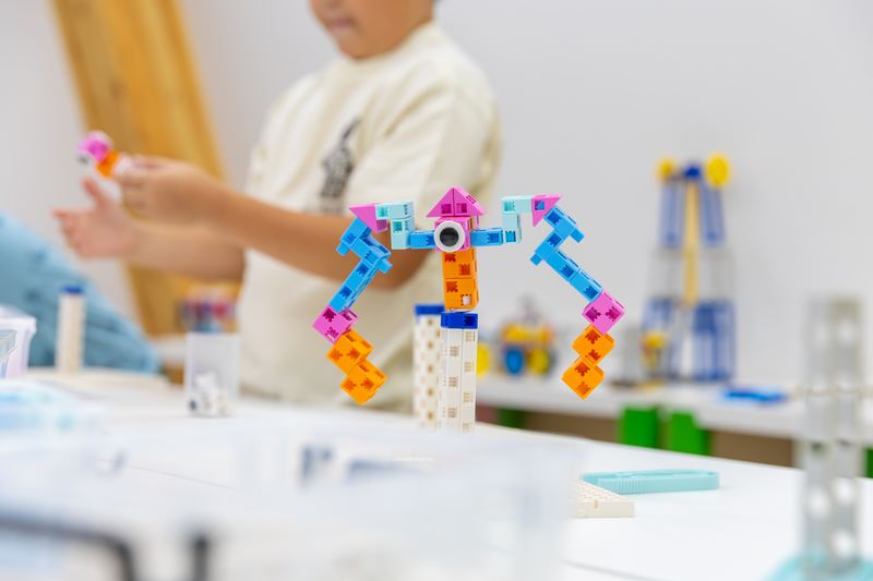 自分で組み立てたロボットを手に取って確かめる小学生