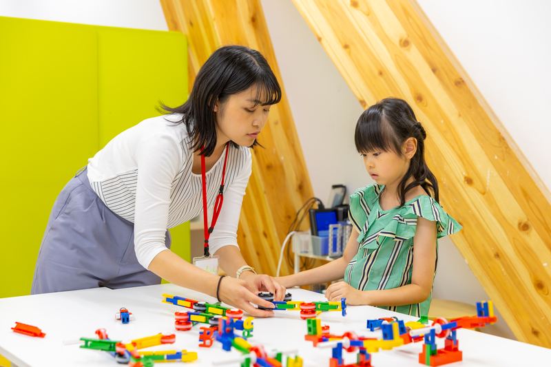 先生と一緒にブロックの課題に取り組む年長の子ども