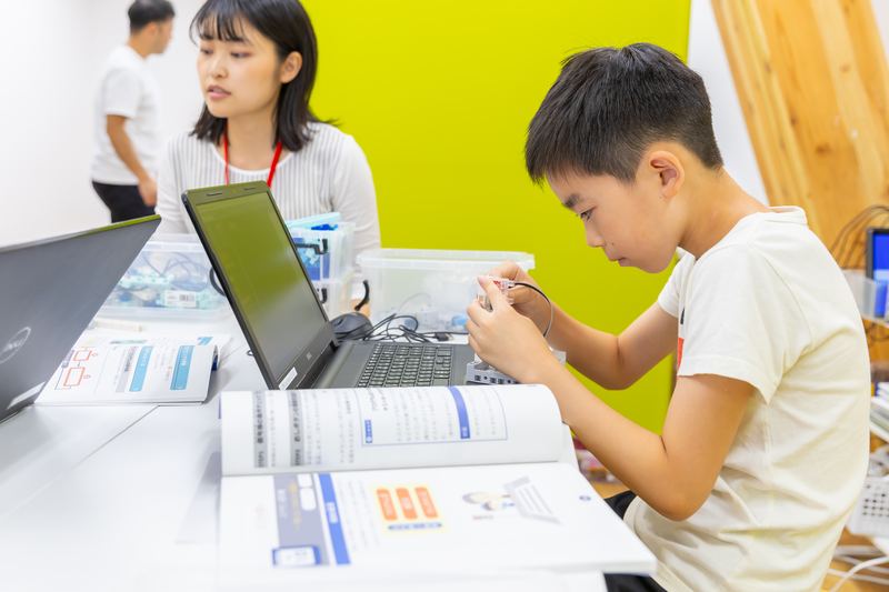 パソコンでプログラムを組み立てる小学生