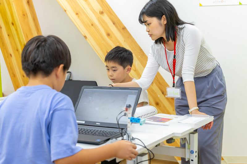 パソコンに向かって作業する生徒と先生
