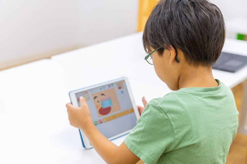 タブレットのプログラミング教材に取り組む小学生